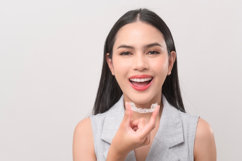 young woman holding Invisalign - understanding how long does Invisalign take