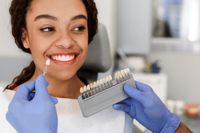 woman receiving dental veneers and checking the samples