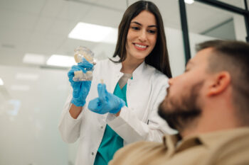 female dentist showing teeth model of what a tooth veneer looks like 