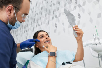 young woman examining her dental veneers at dentist